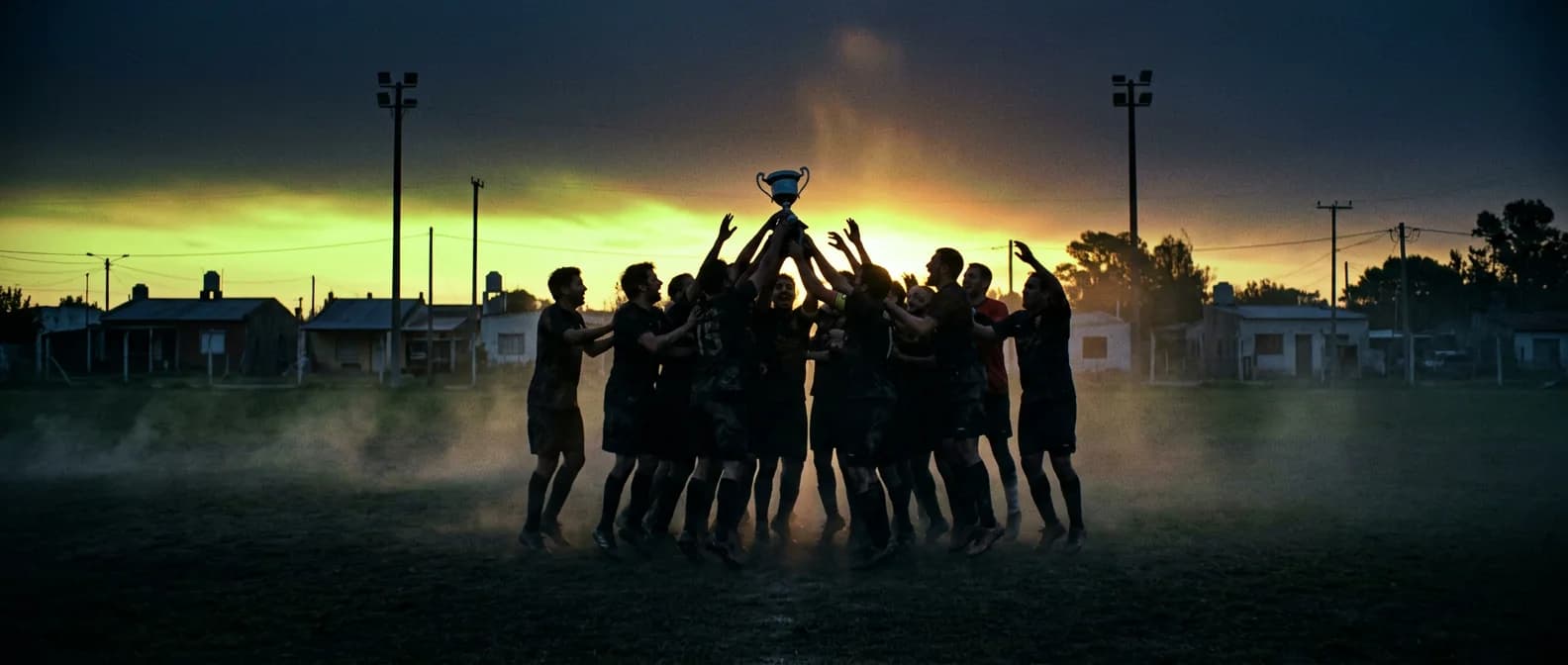 Un equipo levanta la copa a contraluz al caer la tarde en una cancha de barrio